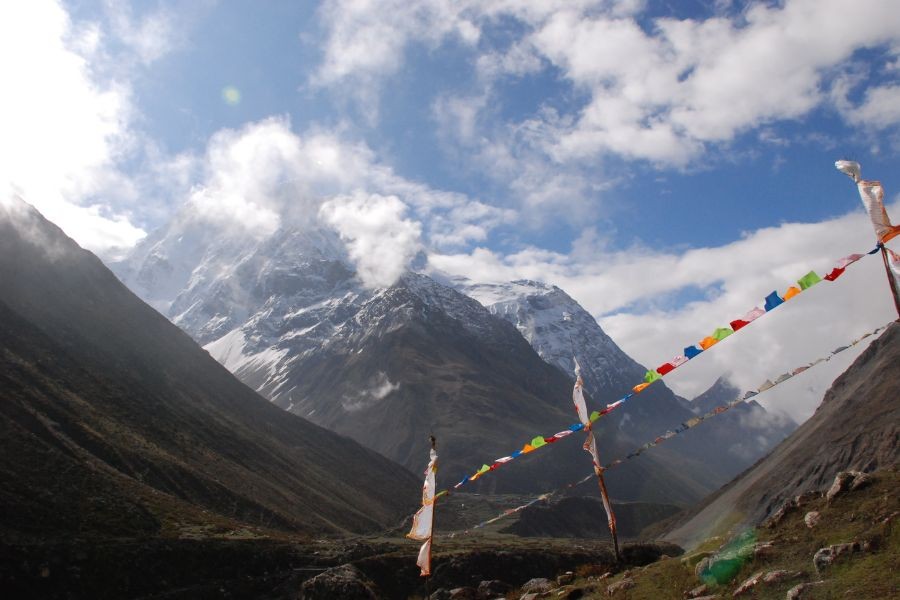 Colorful prayer flags strung across mountain valley with snow-covered peaks